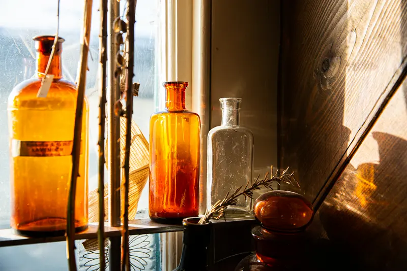 Bernsteinfarbene Glasflakons im warmen Fensterlicht